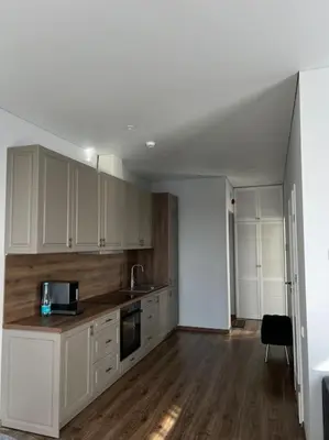 an empty kitchen with white cabinets and a table at Kaunorama apartamentai prie Žalgirio arenos in Kaunas