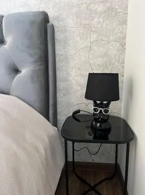 a table with a lamp on it next to a bed at Kaunorama apartamentai prie Žalgirio arenos in Kaunas