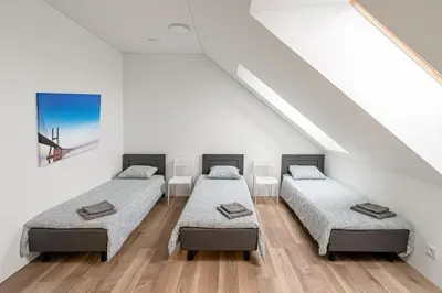 three beds in a room with white walls and wooden floors at Restart in Kaunas