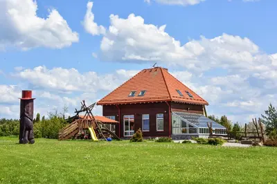a large building with a red roof on a field at Sodyba Pas Drambliuka in Svėdasai