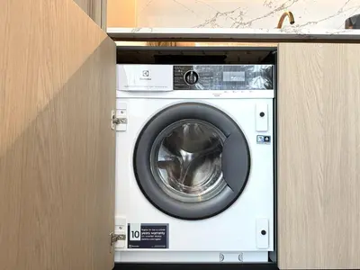 a white washing machine in a cabinet in a kitchen at Apartment near Hospital Kaunas Clinics in Kaunas