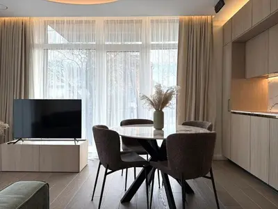 a dining room with a table and chairs and a television at Apartment near Hospital Kaunas Clinics in Kaunas