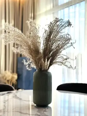 a green vase with a plant sitting on a table at Apartment near Hospital Kaunas Clinics in Kaunas