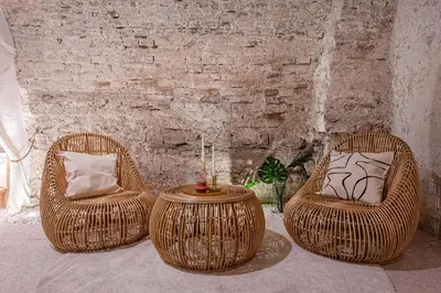 two wicker chairs and a table in front of a brick wall at Aura Spa in Vilnius