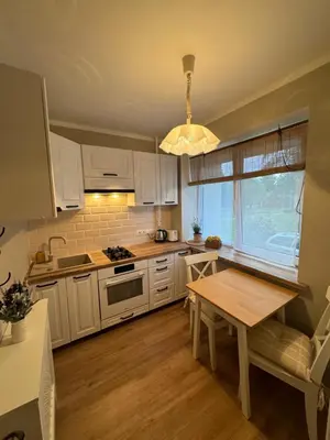a kitchen with white cabinets and a wooden table at Jaukus apartamentas Birzu centre in Biržai