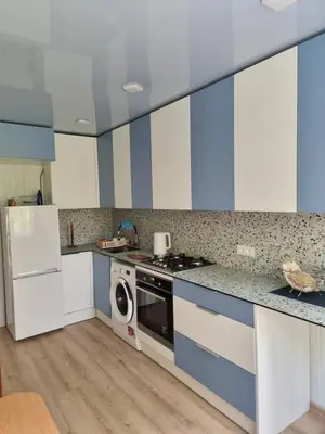 a kitchen with blue and white cabinets and a washer at Kaunas 174 in Kaunas