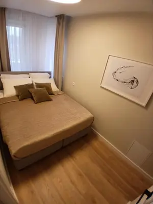 a small bedroom with a bed and a painting on the wall at Kaja Home in Šiauliai