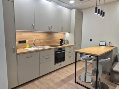 a kitchen with white cabinets and a wooden table at New Kreves apartment & Free parking & Self check-in in Kaunas