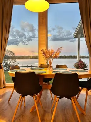 a dining room with a table and chairs and a large window at Sodyba Po klevu in Molėtai