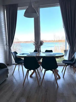 a dining room with a table and chairs and a large window at Sodyba Po klevu in Molėtai