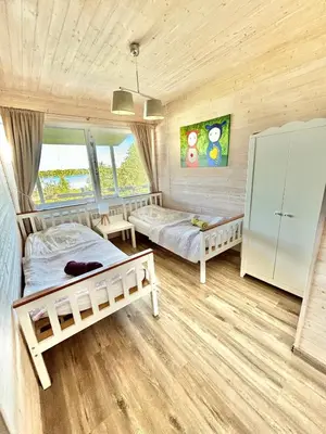 a bedroom with two beds and a large window at Sodyba Po klevu in Molėtai