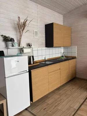 a kitchen with a white refrigerator and wooden cabinets at Sodyba Po klevu in Molėtai