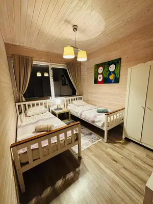 two beds in a room with wooden walls at Sodyba Po klevu in Molėtai
