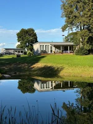 a house with a pond in front of it at Sodyba Po klevu in Molėtai
