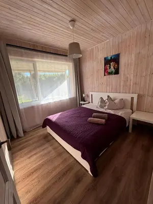 a bedroom with a bed with purple sheets and a window at Sodyba Po klevu in Molėtai