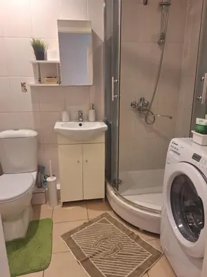 a bathroom with a shower toilet and a washing machine at Rinktinės apartments in Vilnius