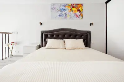a white bedroom with a large bed with white sheets at Edvin Loft x Free parking in Vilnius