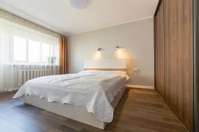 a bedroom with a bed and a large window at Town Square Apartment in Panevėžys