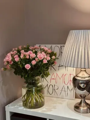 a vase of pink flowers sitting on a table next to a lamp at Studio FAMILY like home in Vilnius