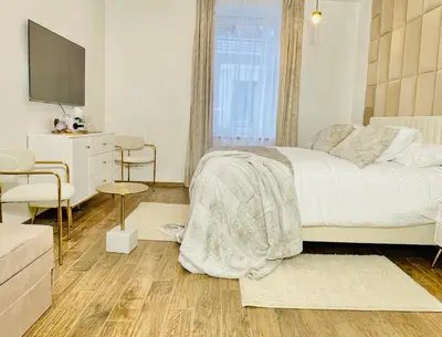 a bedroom with a white bed and a television at IN ROOM Old town Kaunas in Kaunas