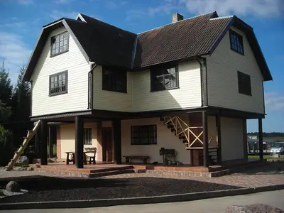 a large white house with a gambrel roof at Sodyba Žabynė in Degyany
