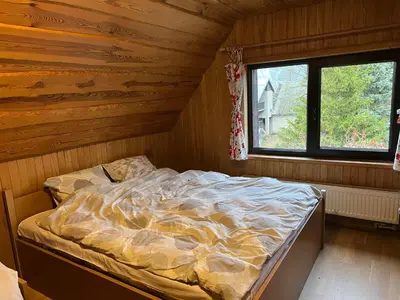 a bedroom with a bed in a wooden cabin at Sodyba Žabynė in Degyany