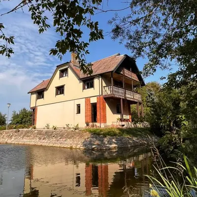 an old house on the edge of a body of water at Sodyba Žabynė in Degyany