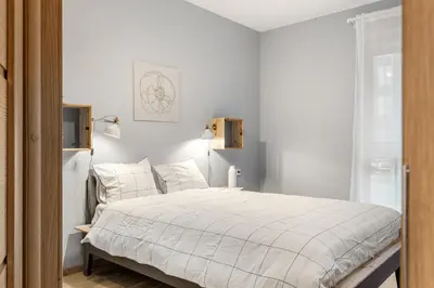 a white bedroom with a bed with white sheets and pillows at Cozy 55m2 Zverynas Retreat with Lodge in Vilnius