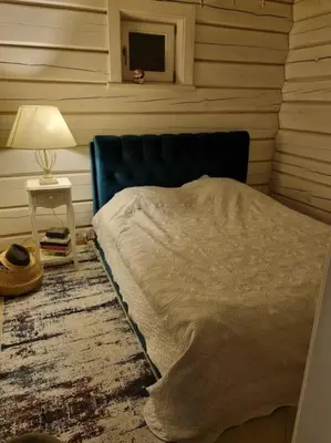 a bedroom with a bed and a table with a lamp at Jauki Trobelė in Aukštelkai