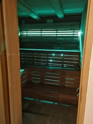 a room with a wooden bench with green lights at Jauki Trobelė in Aukštelkai