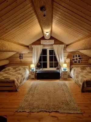 a attic room with two beds and a window at Jauki Trobelė in Aukštelkai