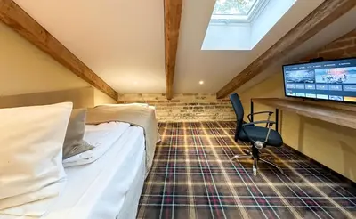 a bedroom with a bed and a desk and a television at New Town Home 1 in Vilnius