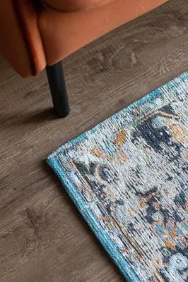 a rug sitting on the floor next to a chair at Petit Retreat Loft by URBAN RENT in Kaunas