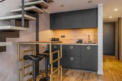 a kitchen with black cabinets and a bar with stools at Petit Retreat Loft by URBAN RENT in Kaunas