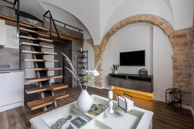 a living room with a spiral staircase and a table at EIM apartment in Vilnius