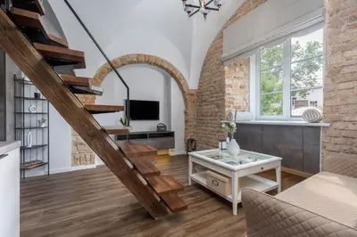 a living room with a spiral staircase and a couch at EIM apartment in Vilnius