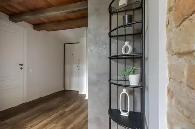 a black shelving unit in a living room and a hallway at EIM apartment in Vilnius