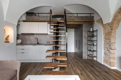 a spiral staircase in a kitchen with white cabinets at EIM apartment in Vilnius