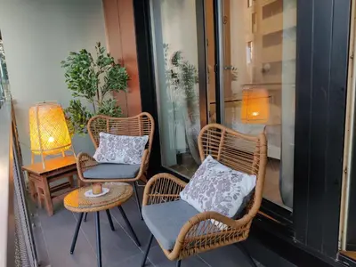 a balcony with three chairs and a table with a lamp at Pilies VIP apartaments in Vilnius
