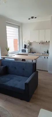 a living room with a blue couch in a kitchen at SKY Studio flat in Panevėžys