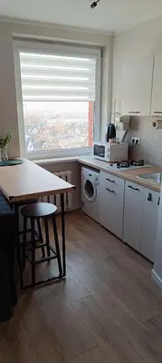 a kitchen with a table and a sink and a window at SKY Studio flat in Panevėžys