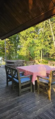 a table and benches on a deck with a table and chairs at Asvejos sodyba in Skirlėnai