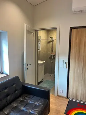 a living room with a black leather couch and a bathroom at Beržo Kampelis Mieste in Kaunas