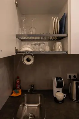 a kitchen with a sink and a shelf with dishes at Bright Vilnius Center Apartment in Vilnius