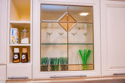 a glass cabinet with wine glasses in it at Charming Apartment with Private Yard in Marijampolė