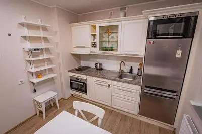 a kitchen with white cabinets and a stainless steel refrigerator at Charming Apartment with Private Yard in Marijampolė