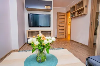 a vase of flowers on a table in a living room at Charming Apartment with Private Yard in Marijampolė