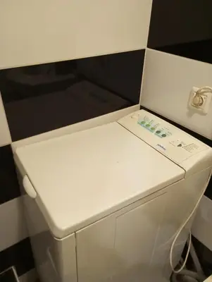 a small white refrigerator in a room with black and white tiles at Butas centre šalia pėsčiųjų bulvaro in Šiauliai
