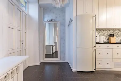 a white kitchen with a refrigerator and a window at Next to Cathedral Square, Stylish 2BD Gem, Skapo St in Vilnius