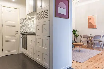 a kitchen with white cabinets and a table in a room at Next to Cathedral Square, Stylish 2BD Gem, Skapo St in Vilnius